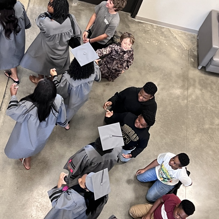 High school seniors in the caps and gowns walking the halls of McCalla Elementary