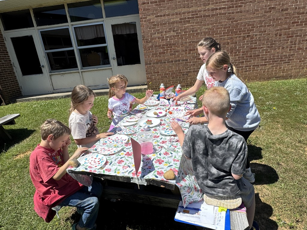 4th grade girls assist younger students to complete a garden craft using construction paper and paper plates.