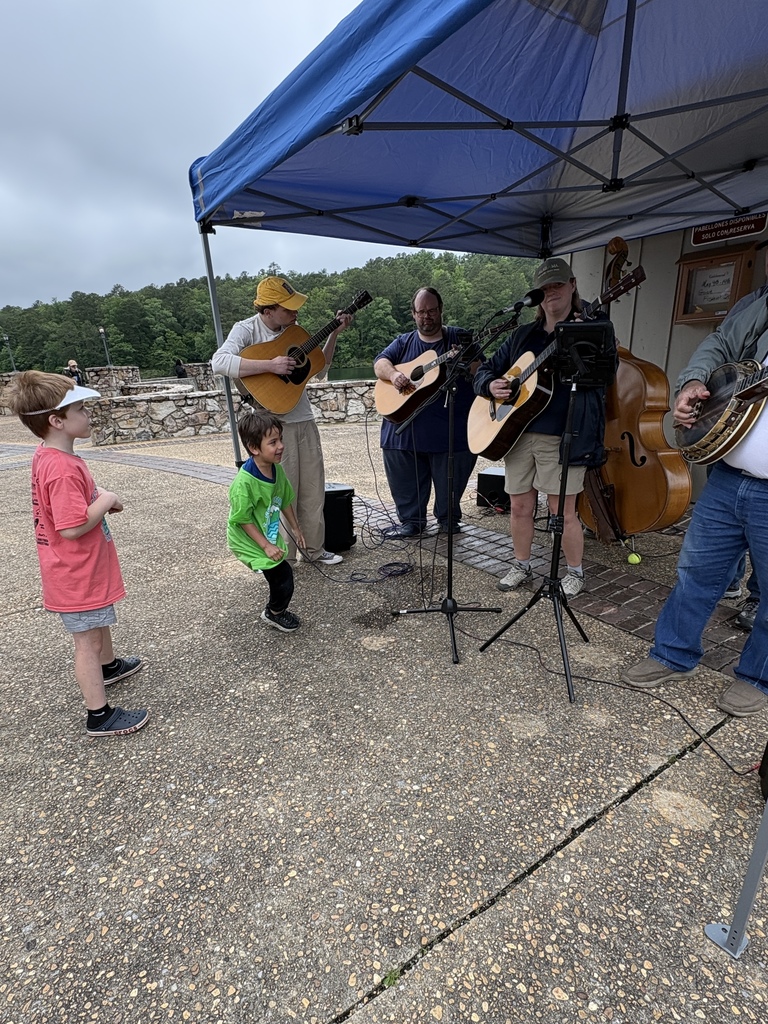 A group of students dance outdoors as a band plays.