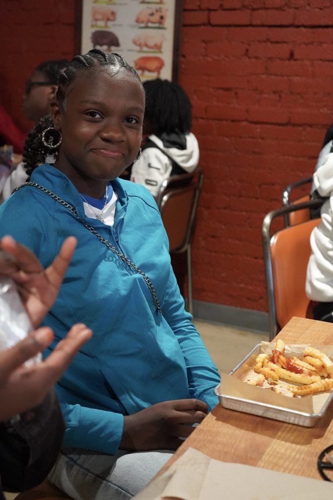 A student smiles while sitting at a table at a restaurant .