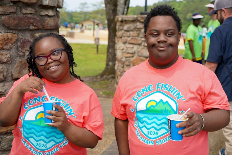 A boy and a girl stand together for a photo outside. They hold slushies in their hands.