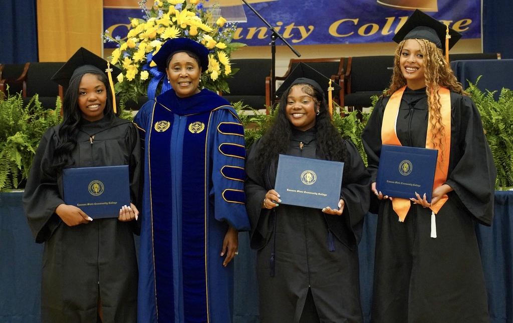 JEFCOED dual enrollment graduates stand together for a photo with the president of Lawson State Community College. They all wear graduation robes and caps.