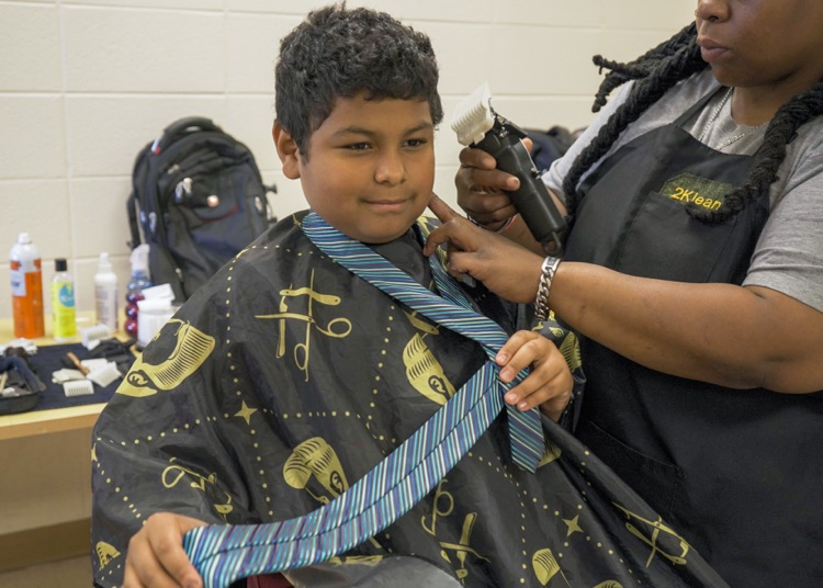 A woman cuts a boy’s hair.