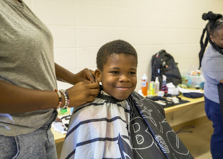 A boy smiles while getting his hair cut  