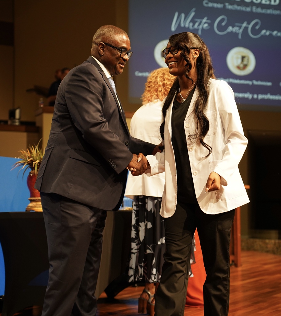 A girl smiles as she shakes Superintendent Dr. Walter Gonsoulin's hand during the JEFCOED White Coat Ceremony.