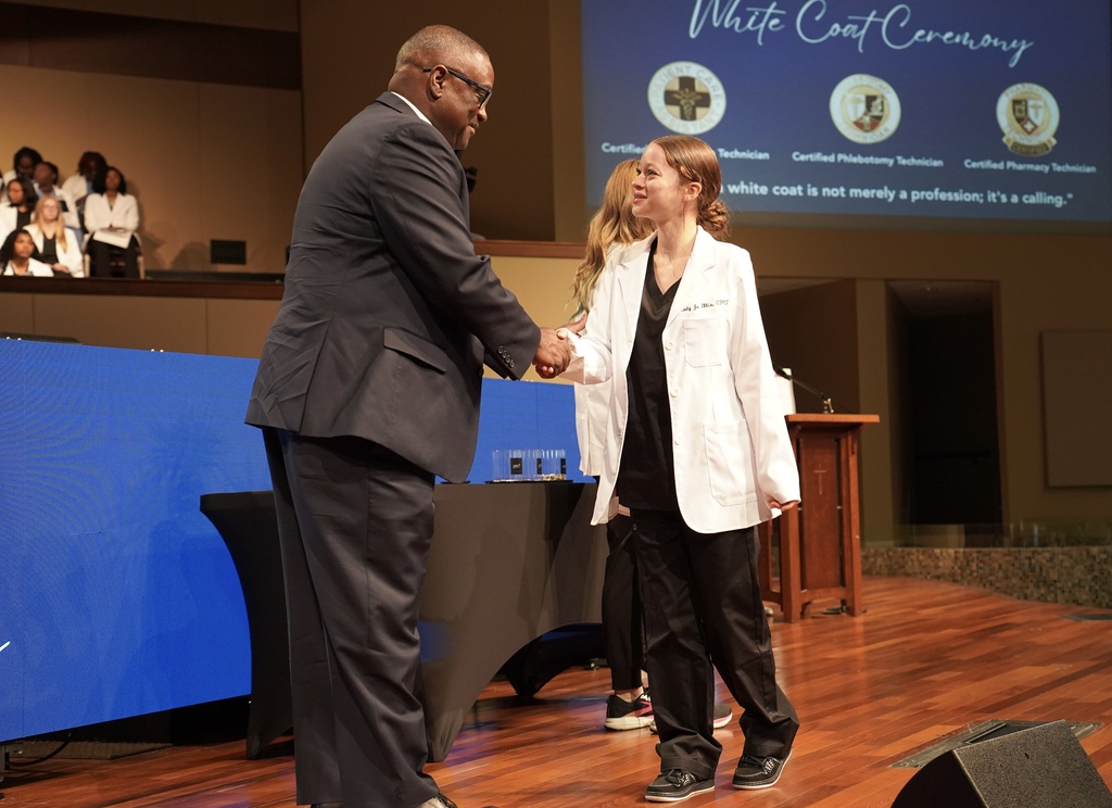 A girl smiles as she shakes Superintendent Dr. Walter Gonsoulin's hand during the JEFCOED White Coat Ceremony.