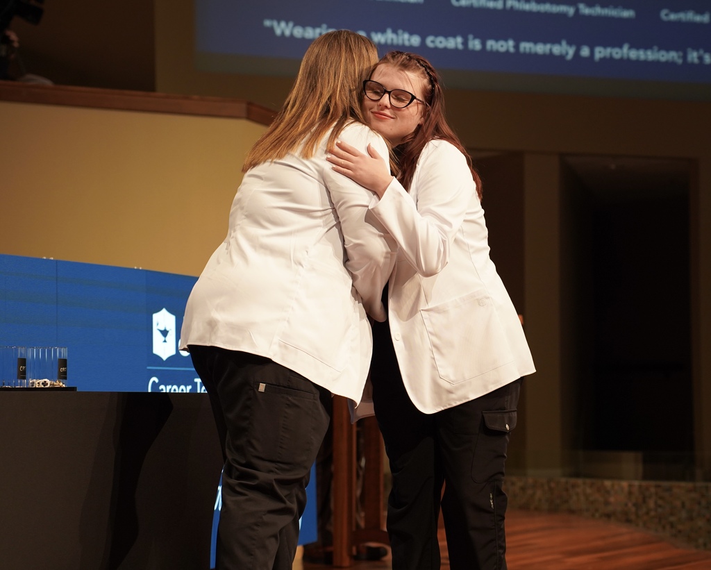 A girl hugs a teacher during the JEFCOED White Coat Ceremony.
