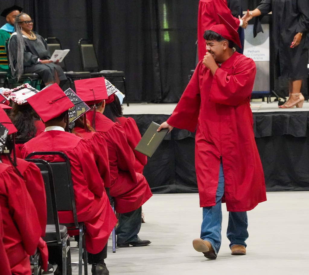 A student smiles while walking down an aisle at the Shades Valley High School graduation ceremony.