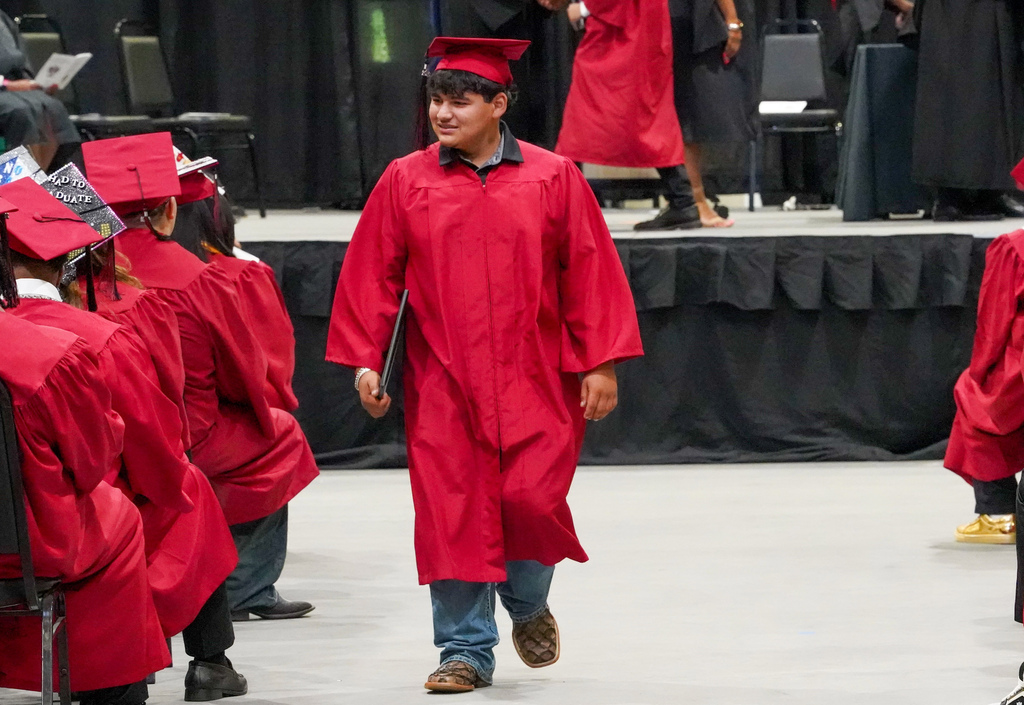 A student smiles while walking down an aisle at the Shades Valley High School graduation ceremony.