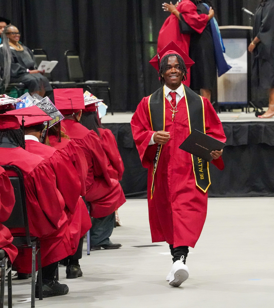 A student smiles while walking down an aisle at the Shades Valley High School graduation ceremony.
