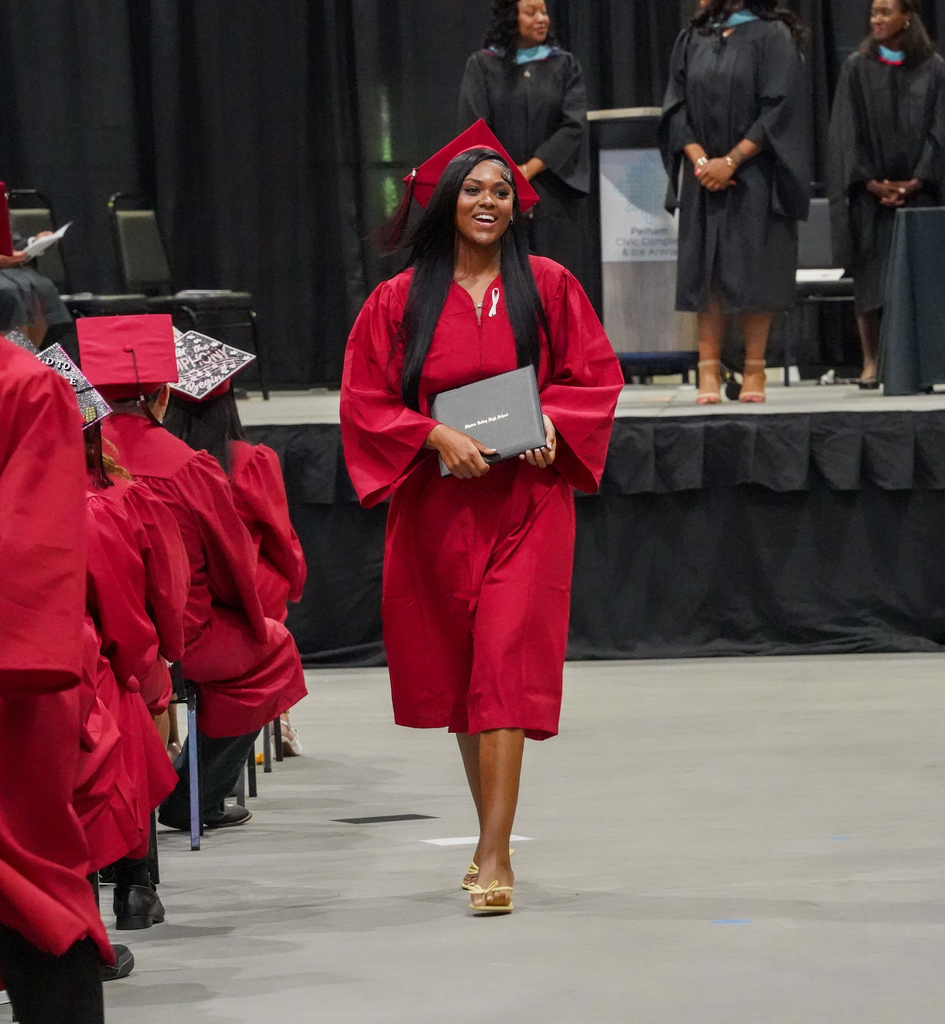 A student smiles while walking down an aisle at the Shades Valley High School graduation ceremony.