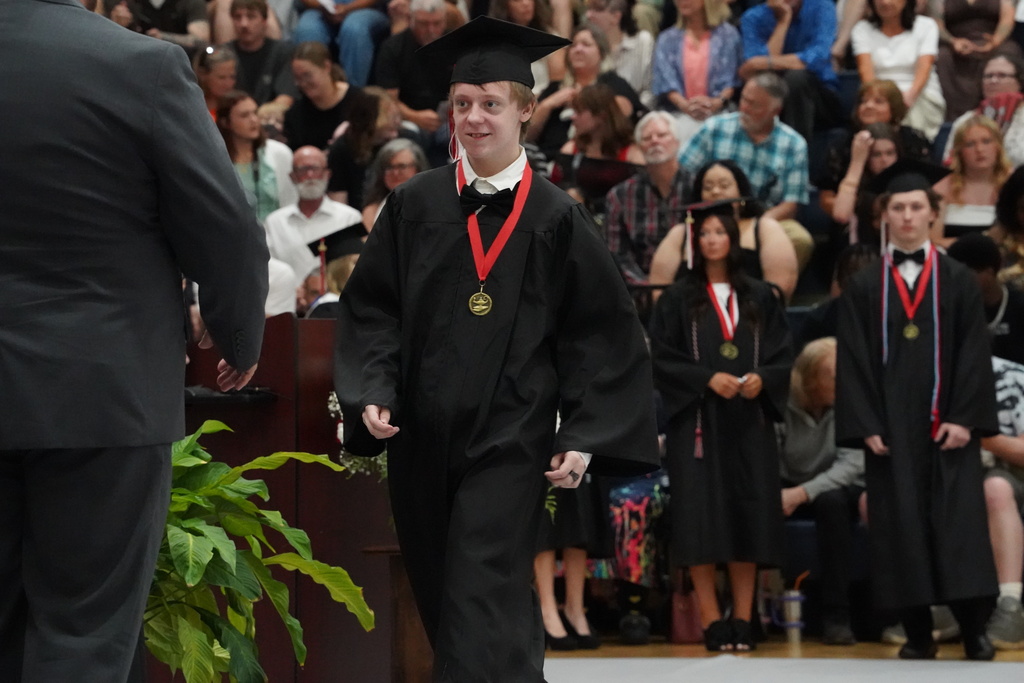 A student smiles while walking to receive his diploma during Oak Grove High School's graduation ceremony.