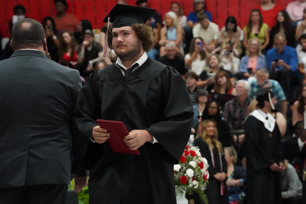 A student holds his diploma and walks to his seat during the Oak Grove graduation ceremony.