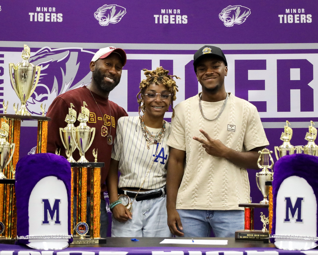 A band student student takes a picture with friends and family during signing day at Minor High School.
