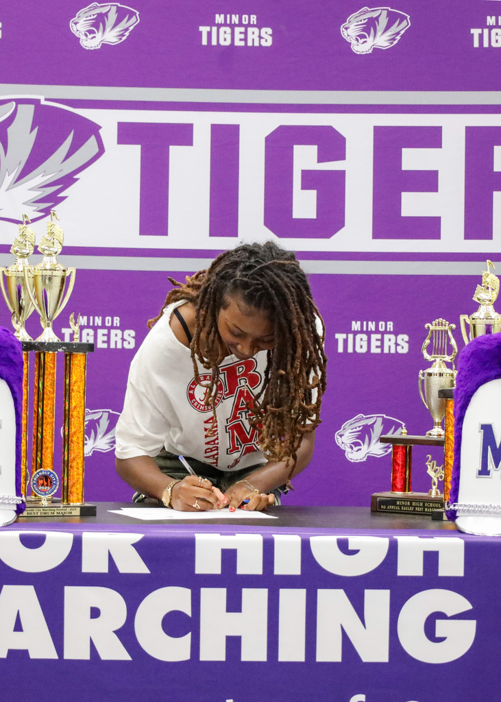 A Minor High School band student signs a piece of paper during a 2025-2026 signing day event. 