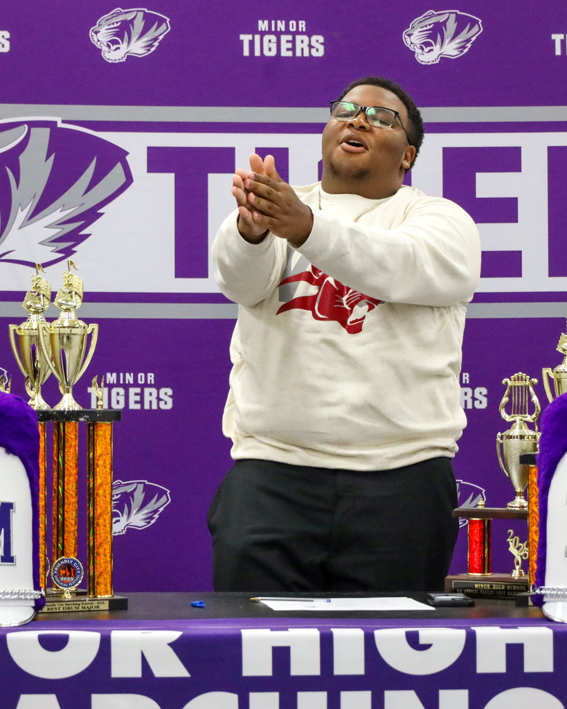 A Minor High School band student holds up his hands as if clapping during signing day. 