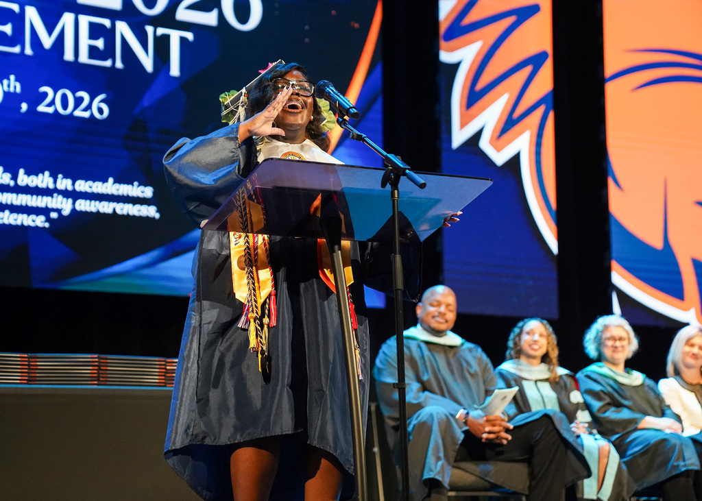 A student speaks from the podium, holding her hand up to her mouth, during the 2026 Fultondale High School Graduation.