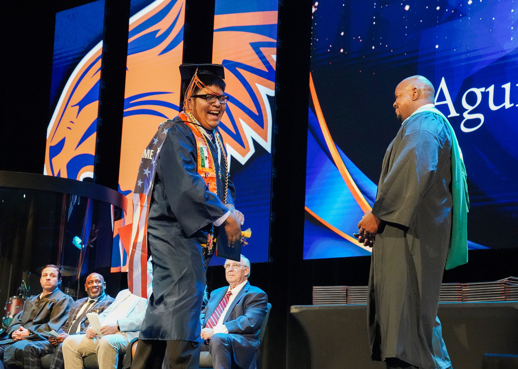 A student joyfully walks across the stage to receive his high school diploma during the 2026 Fultondale High School Graduation.