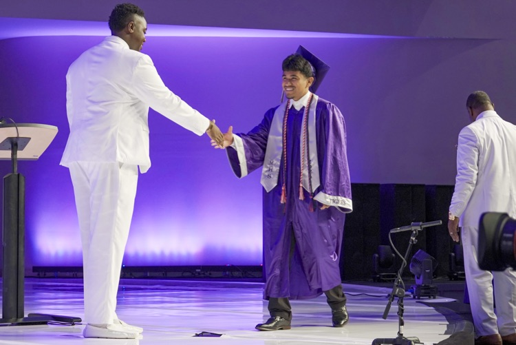 A Minor High School graduate shakes a man’s hand during the high school graduation ceremony
