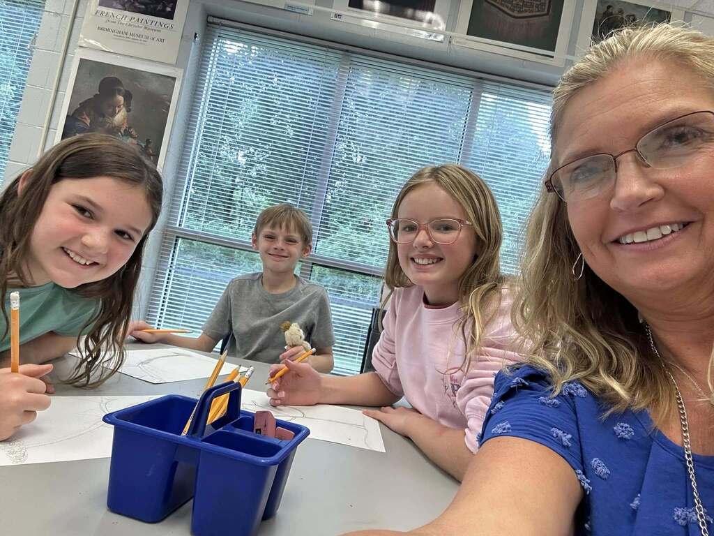 Snow Rogers principal Kristi Long smiles for a selfie with students inside a classroom.