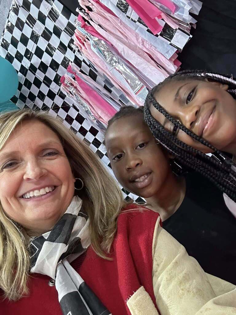 Snow Rogers principal Kristi Long smiles for a selfie with students inside a classroom.