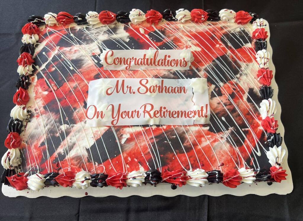 A red, black and white cake says "Congratulations Mr. Sarhaan On Your Retirement".