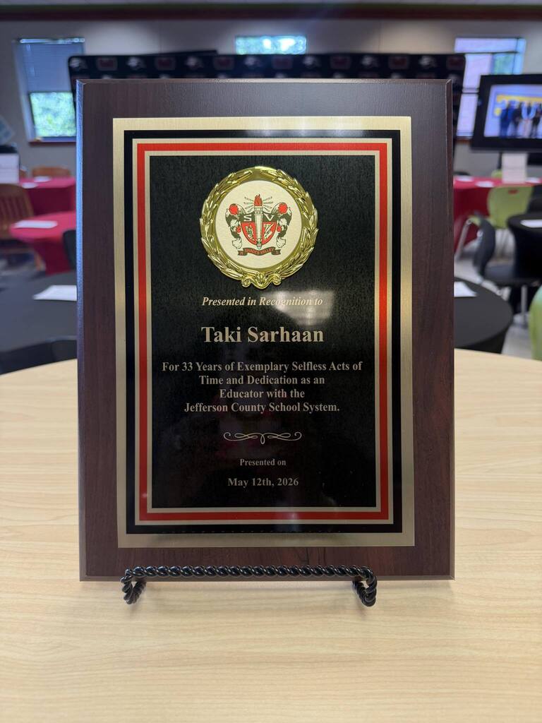 A plaque celebrates the retirement of Taki Sarhaan after 33 years in education.