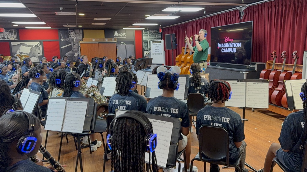 A conductor leads the Clay-Chalkville Middle School band as they sit in chairs behind music stands.