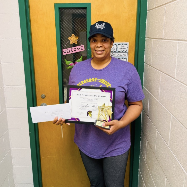 A picture of Ms. Melton holding her award for being the Spartan employee of the month.