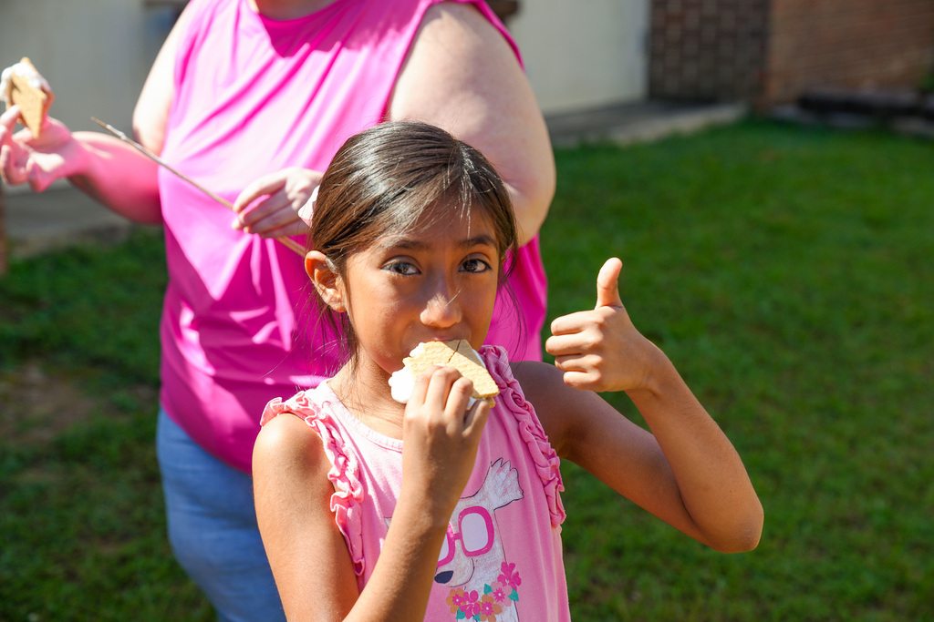 A student gives a thumbs up while eating a s'more.