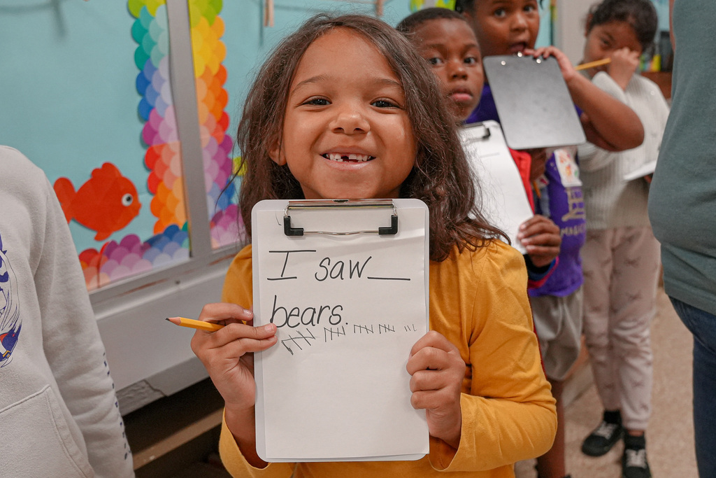 A student holds up a piece of paper marking off how many bears she saw on a scavenger hunt. 