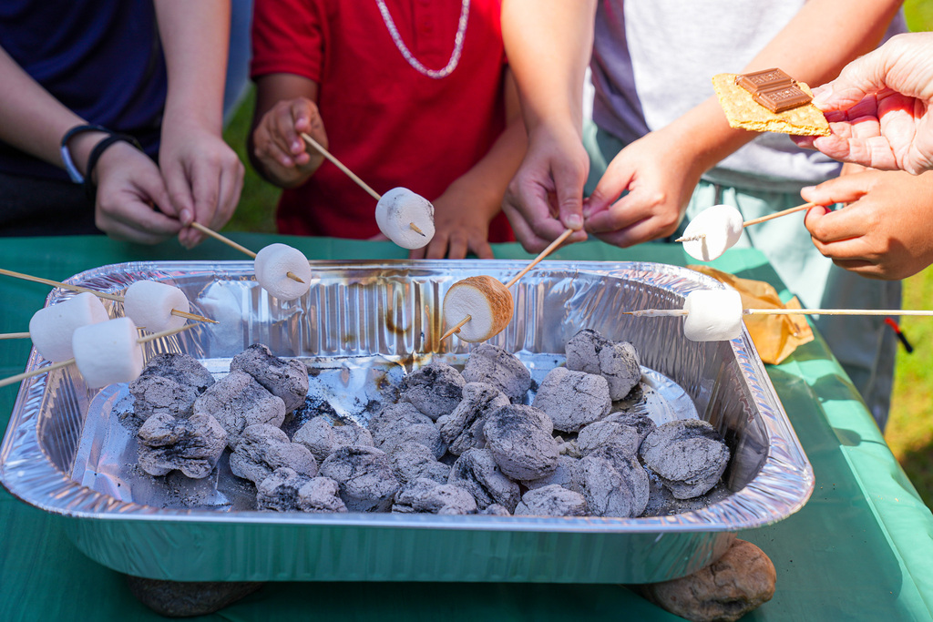 Students roast marshmallows over charcoal.