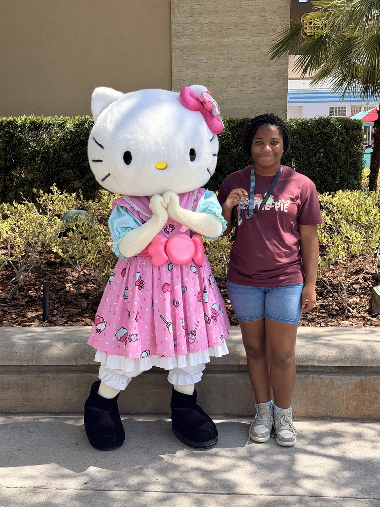 A girl smiles and poses for a photo with a person wearing a Hello Kitty costume.