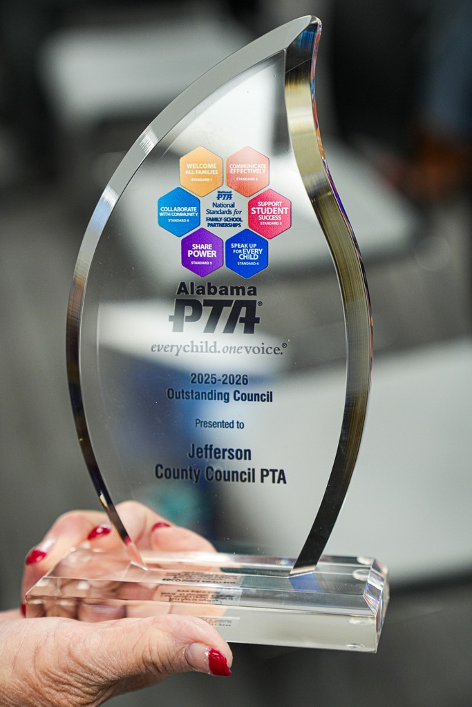 A woman holding the 2025-2026 Outstanding Council Award from the Alabama PTA.