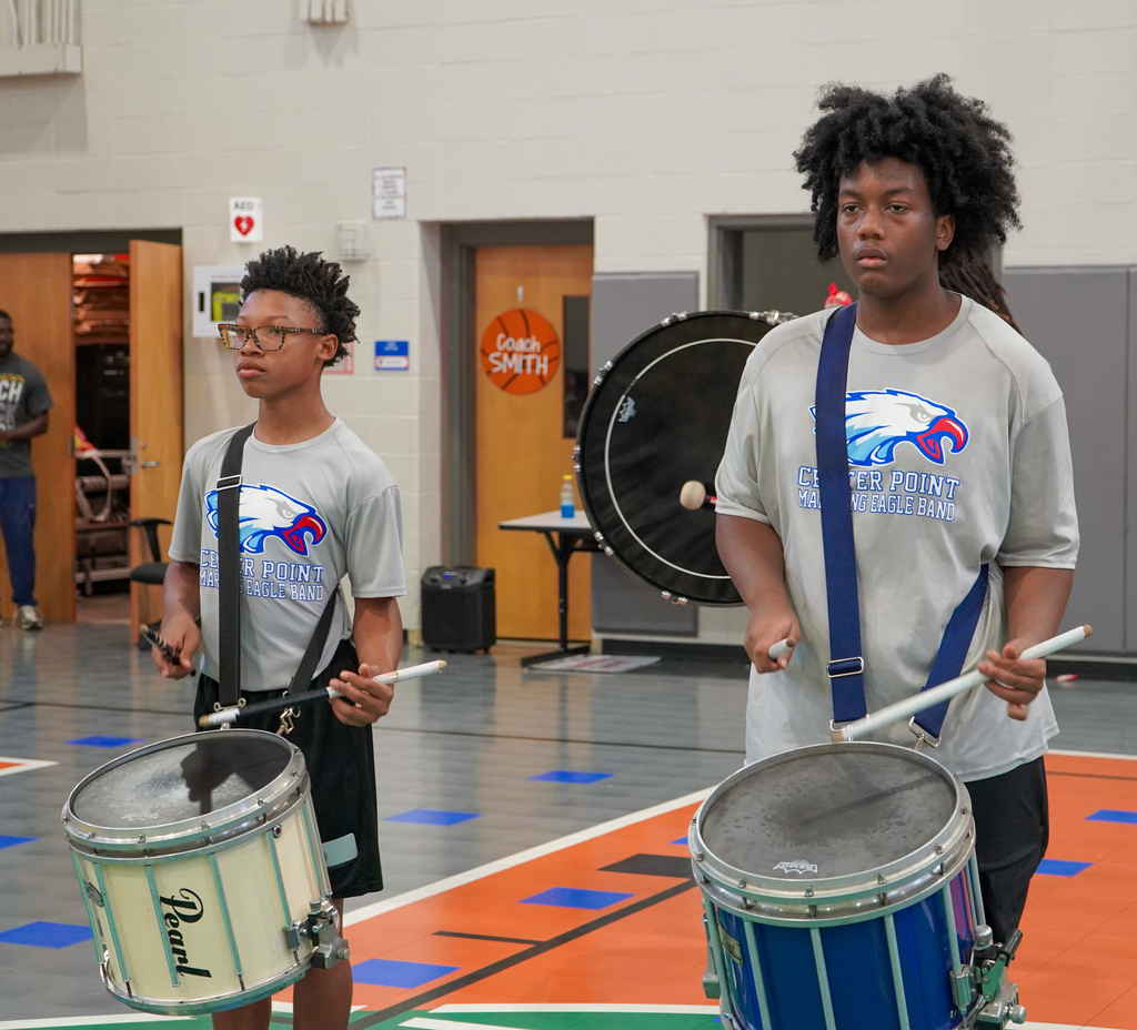 Center Point High School drum line members play snare drums during a performance inside a school gym.