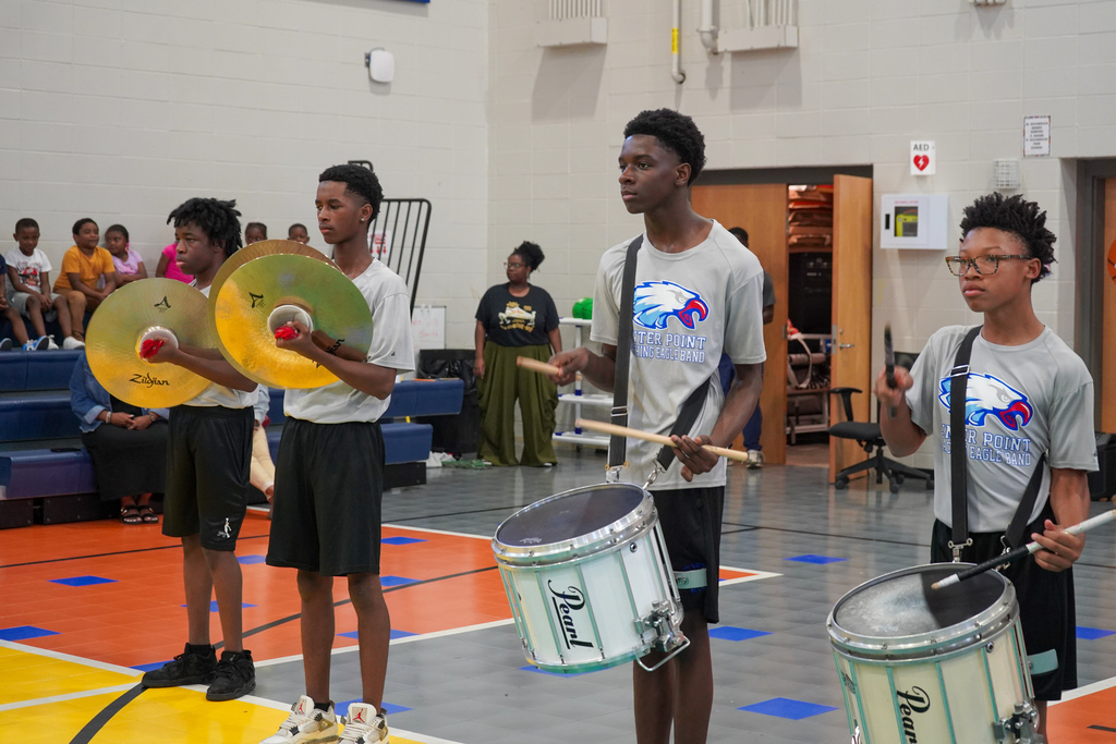 Center Point High School's drum line performs for students inside a school gym. They play drums and the symbols.