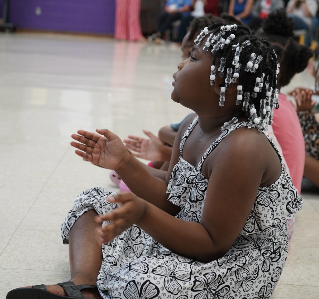 Students clap while listening to a performance inside a school. auditorium.