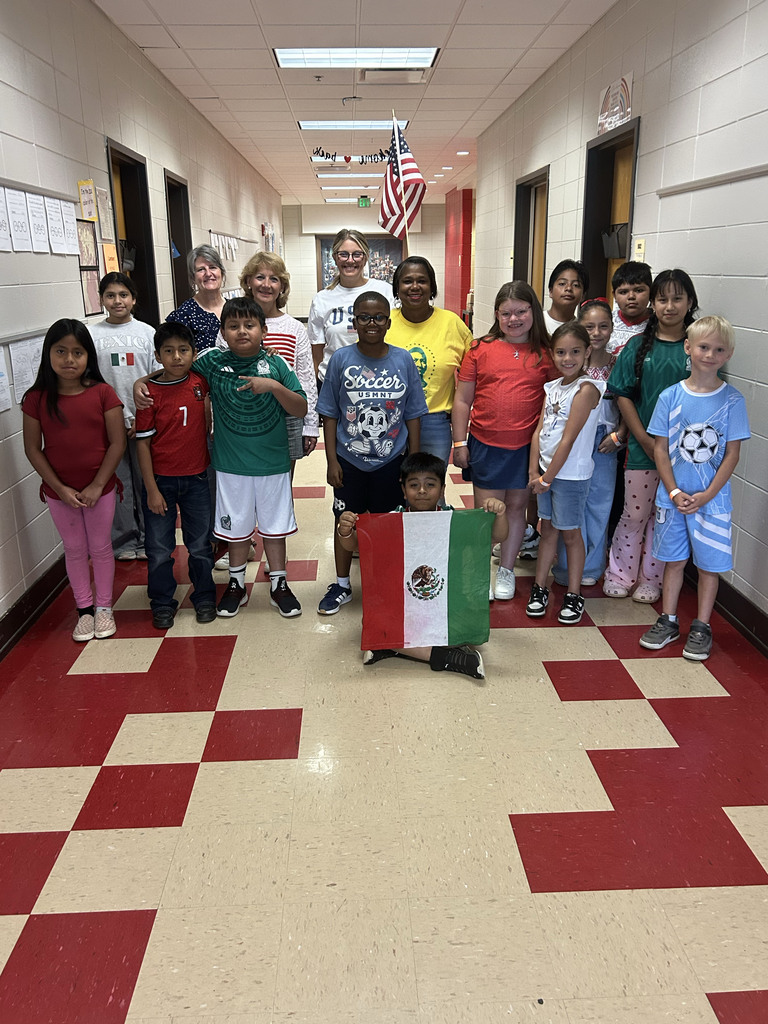 Students stand in a hallway for a photo. They all wear soccer gear, showing support for their favorite teams playing in the World Cup.
