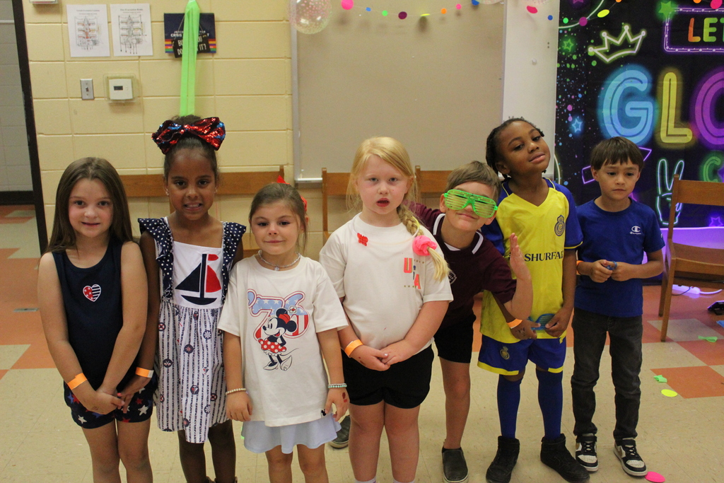A group of students pose for a photo. They wear outfits showing support for their favorite World Cup teams.