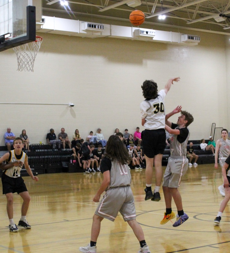 A basketball player blocks another player attempting to shoot a basketball during a game.