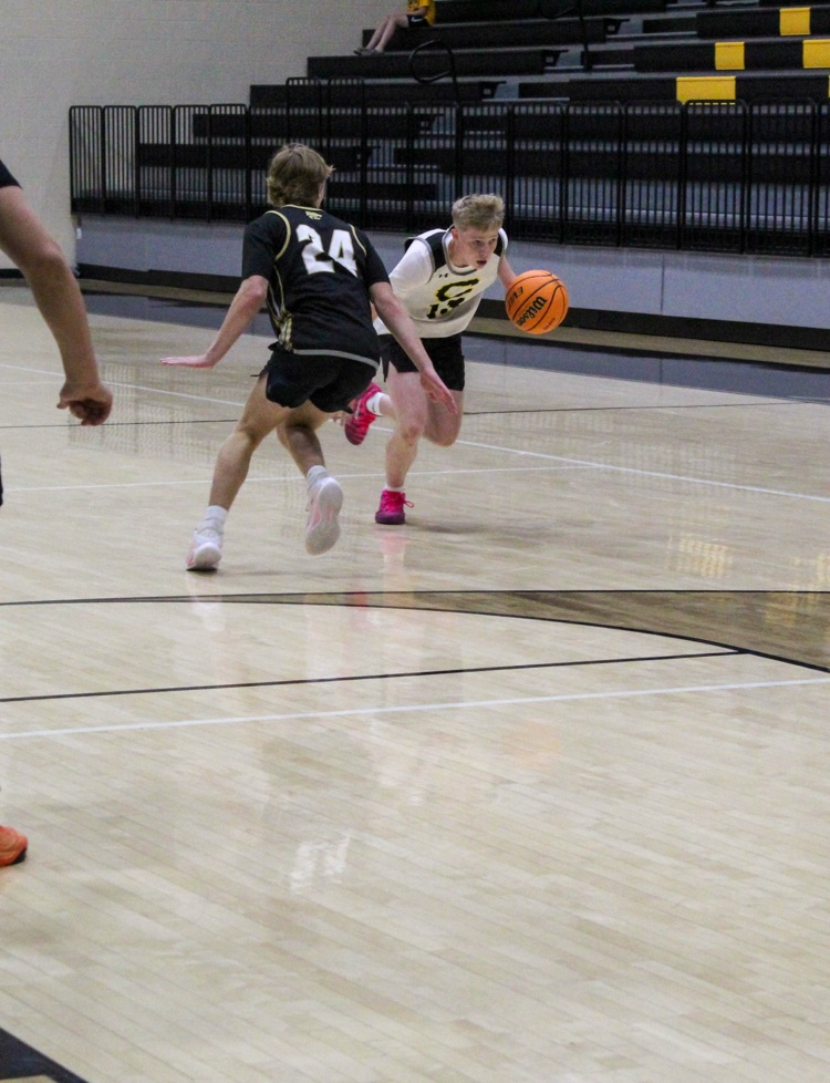 A basketball player runs down the court while dribbling a ball  