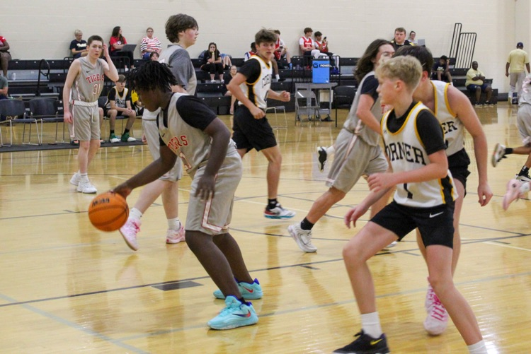 A basketball player dribbles the ball during a game inside a school gym  