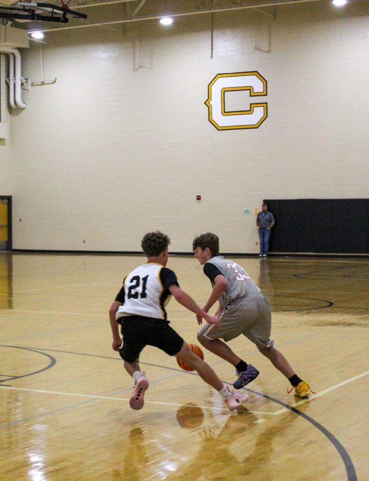 Two players run toward a basketball during a game in a school gym   