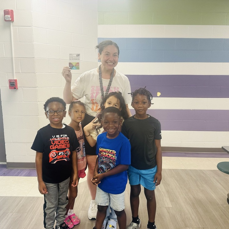 Ms. Gilreath standing with several students in her SOAR class. she is holding the gift card her class won for knowing the song of the week.