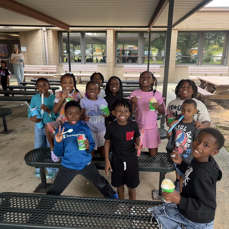 several students from the SOAR program standing around a bench outside while eating an ICEE.