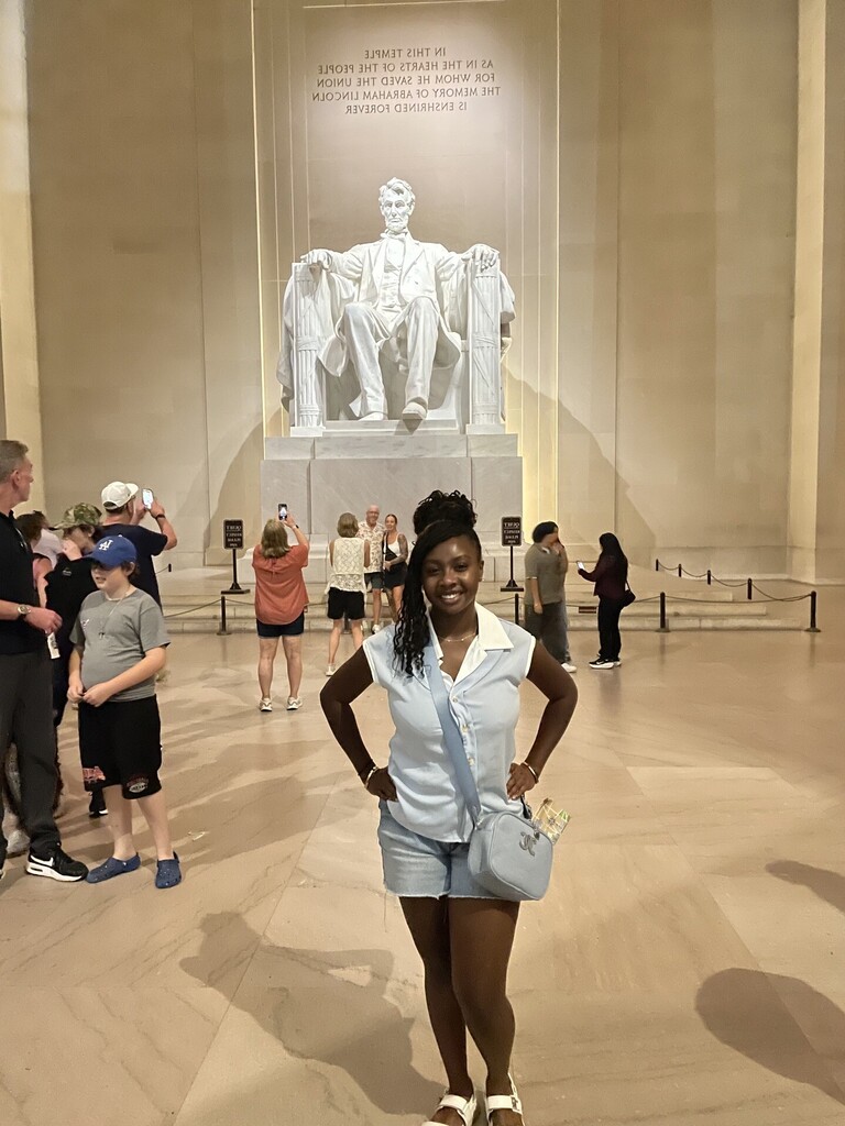 A girl smiles and poses for a photo in front of the Lincoln Memorial.