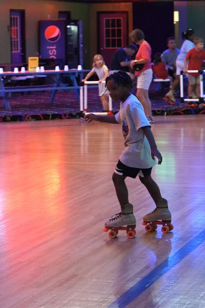 A boy skates across the floor at a skating rink