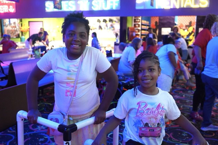Two girls smile while standing in the arcade area of a skating rink