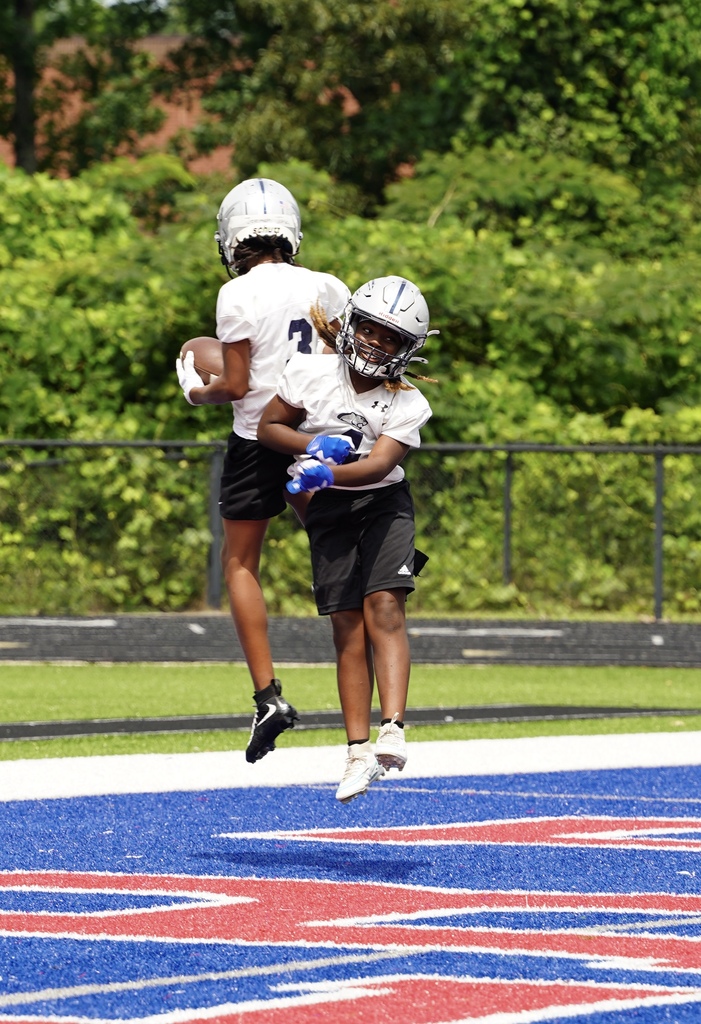 Clay-Chalkville Middle School football players jump toward each other on the end zone to celebrate a touchdown. 