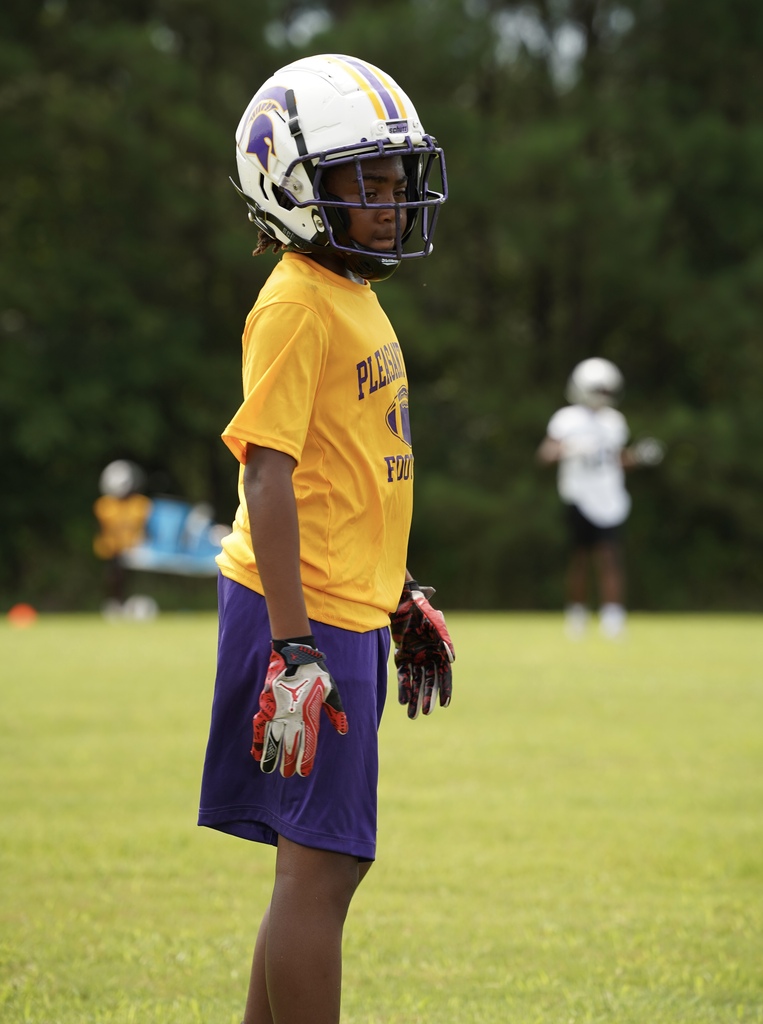 A Pleasant Grove Middle School football player stands on a field during a game.